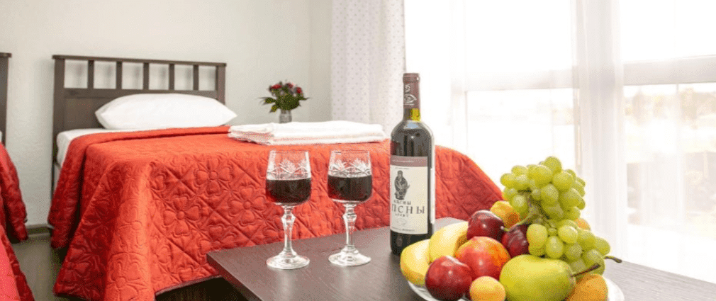 Бутылка вина, два фужера и кровать в отеле СанЗазила, Абхазия.png